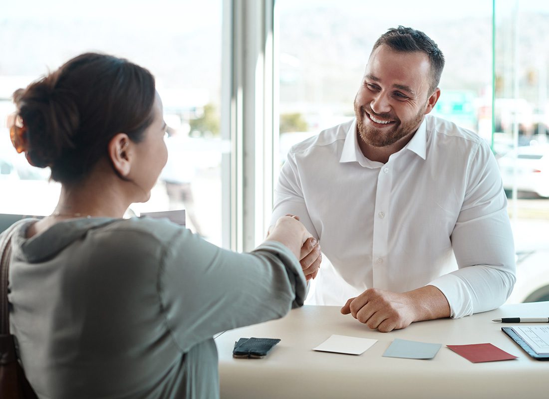 About Our Agency - View of a Cheerful Middle Aged Man Sitting in an Office with a Female Client Shaking her Hand After a Successful Meeting