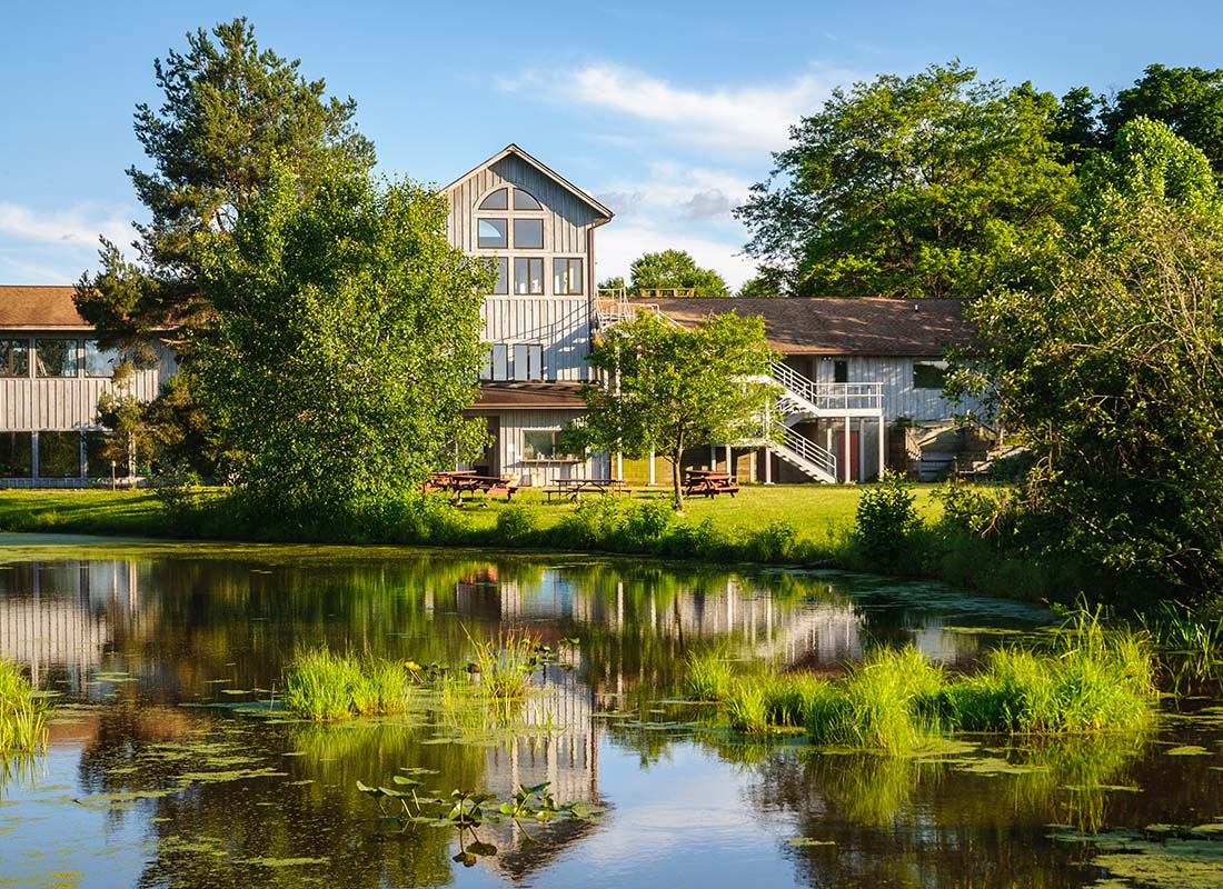 Jamestown, NY - View of a Two Story Building Next to the Lake in a Park with Green Trees in Jamestown New York