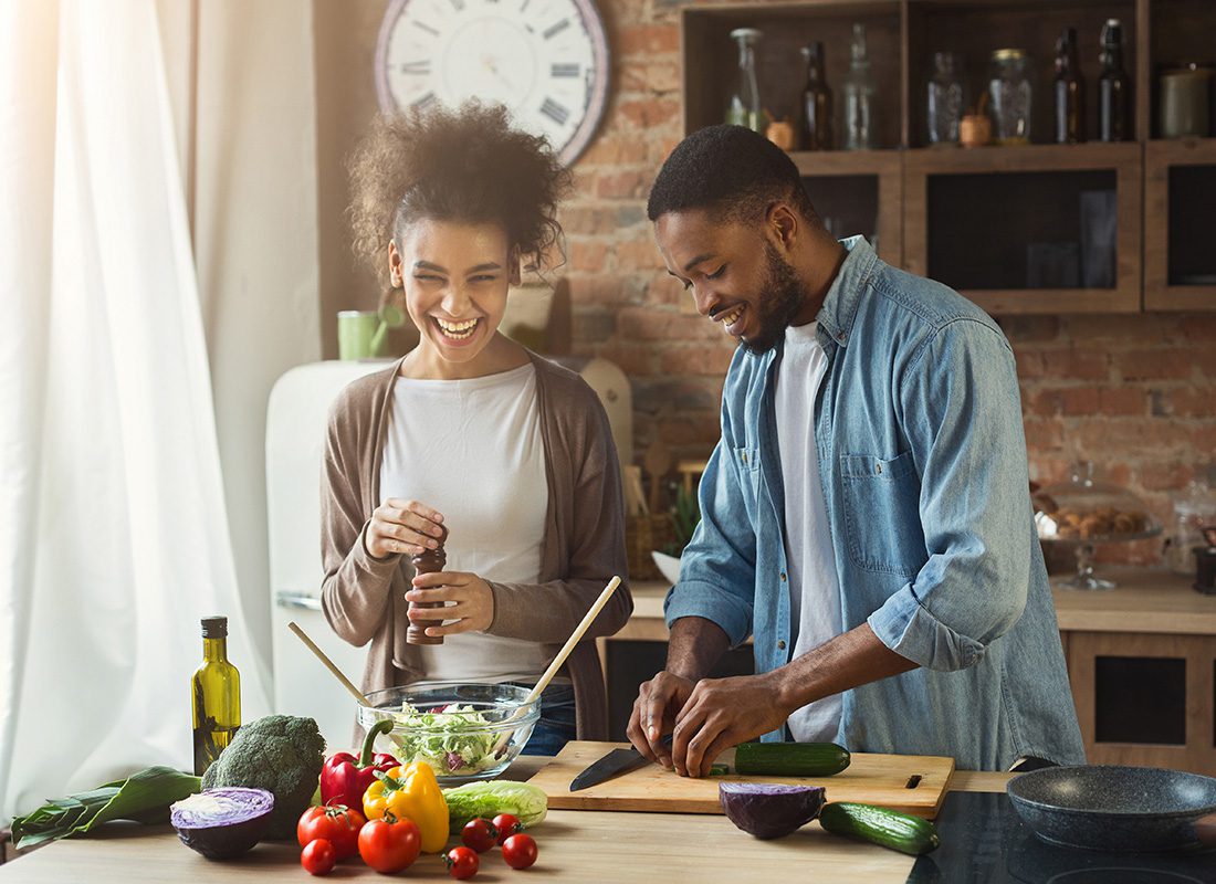 Read Our Reviews - View of a Young Cheerful Married Couple Having Fun Preparing a Salad Together in the Kitchen of Their New Home