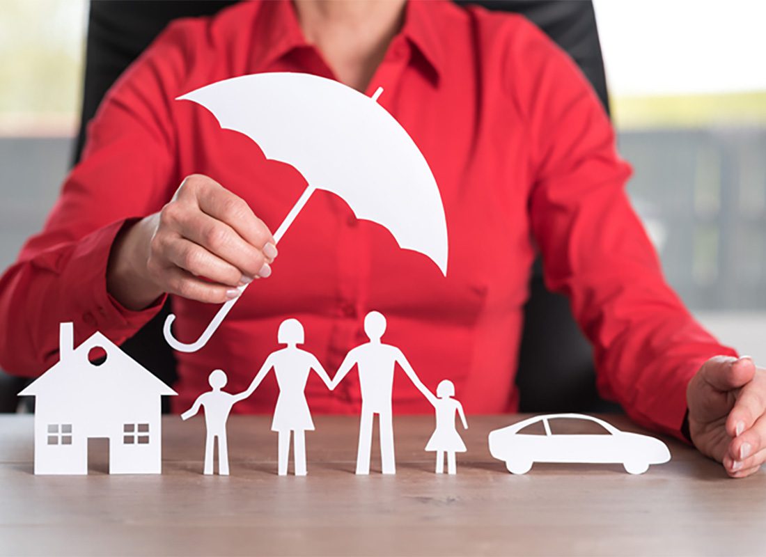 Contact - View of a Woman Wearing a Red Shirt Sitting at her Desk While Holding a Paper Umbrella Over a Family Next to a House and Car on the Table